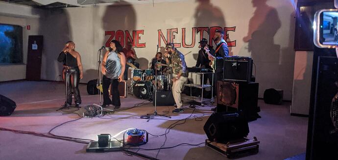 Concert de Rumba Congolaise à Zone Neutre. Les trois musiciens, le chanteur et les deux chanteuses sont accompagnés par Saïd au tambour.